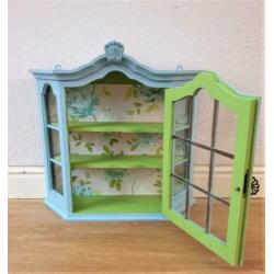 Een blauw met groen vitrine kastje met mooi behang, vogels