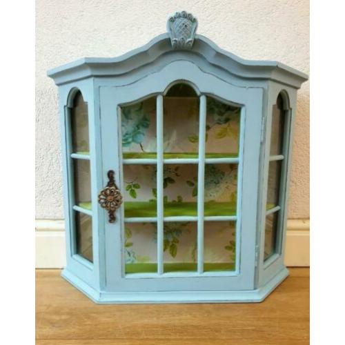Een blauw met groen vitrine kastje met mooi behang, vogels