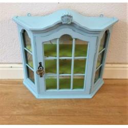 Een blauw met groen vitrine kastje met mooi behang, vogels