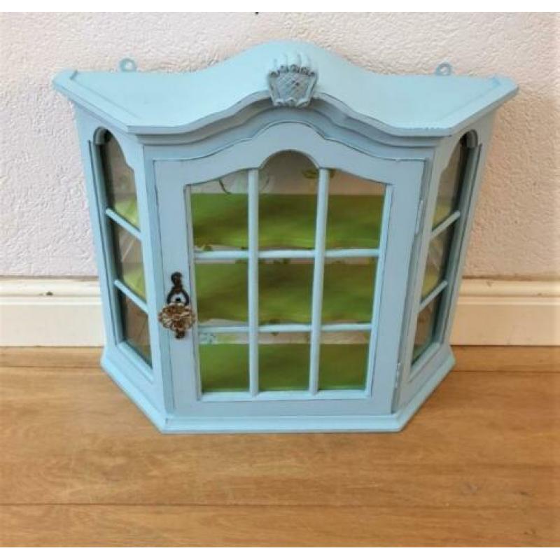 Een blauw met groen vitrine kastje met mooi behang, vogels