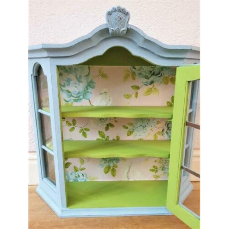 Een blauw met groen vitrine kastje met mooi behang, vogels